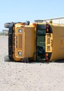 Yellow school bus tipped over with blue sky in background